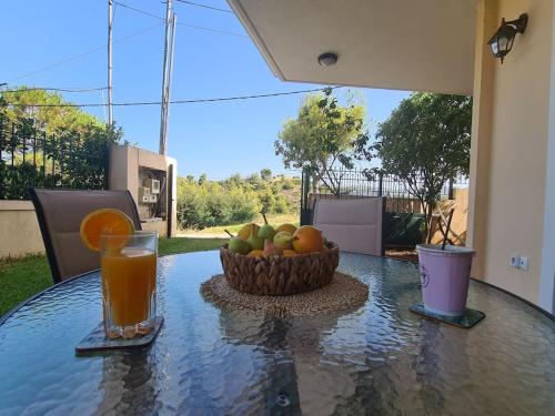 a table with a bowl of fruit and a glass of orange juice at Philoxenia Home Oropos / Just Moments from the Sea in Néa Palátia