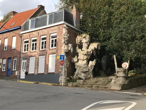 un bâtiment en briques avec une statue d'arbre au bord d'une rue dans l'établissement Cabinet de rêveries #2, à Cassel