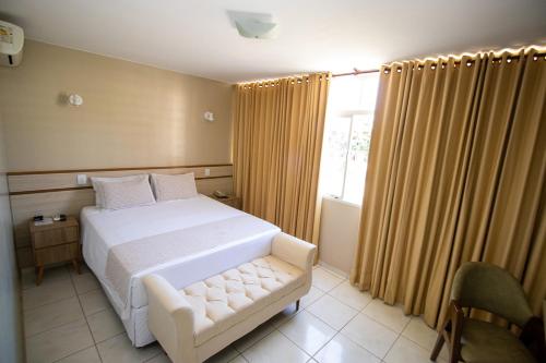 1 dormitorio con cama blanca y ventana en Alvimar Hotel, en Sobradinho