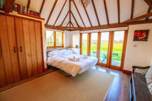 um quarto com uma cama num quarto com janelas em Dairyman's Barn -Rye - Countryside Retreat em Playden