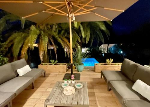 une terrasse avec des canapés et une table avec un parasol dans l'établissement Villa Kiwi, à Sète