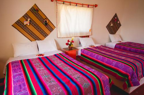 two beds sitting next to each other in a room at TITIKAKA NATURAL LODGE - LUQUINA in Chucuito