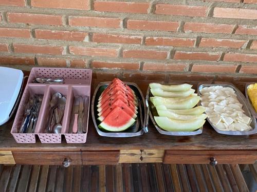 a table with four trays of different types of food at Recanto Filadélfia in Paraty