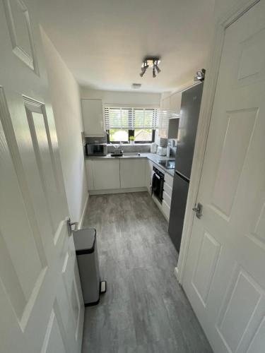eine Küche mit weißen Schränken und einer Tür in einem Zimmer in der Unterkunft Glasgow SECC Hydro River View in Glasgow