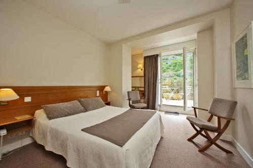 a bedroom with a bed and a desk and a window at Le Terminus des Pèlerins in Rocamadour