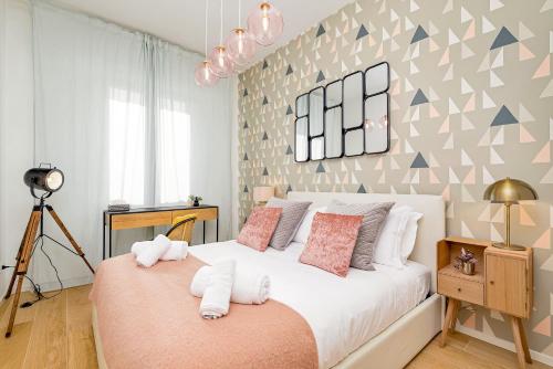 una camera da letto con un grande letto bianco con cuscini rosa di BauHaus - Sleepwithme - Free Parking - Free Braeakfast - Very Friendly Staff a Pisa