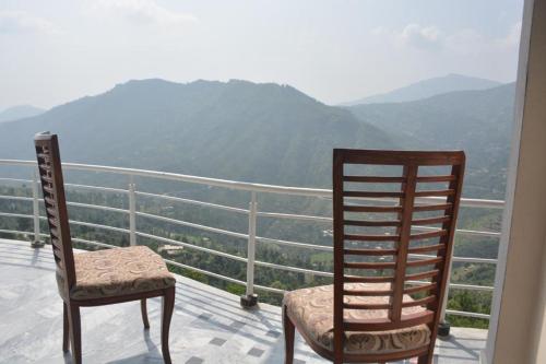 two chairs on a balcony with a view of mountains at Ihram Hotel And Guest House in Swat