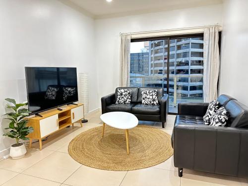 uma sala de estar com um sofá e uma televisão em 2 Bedroom Apartment @ Grenfell Street em Adelaide