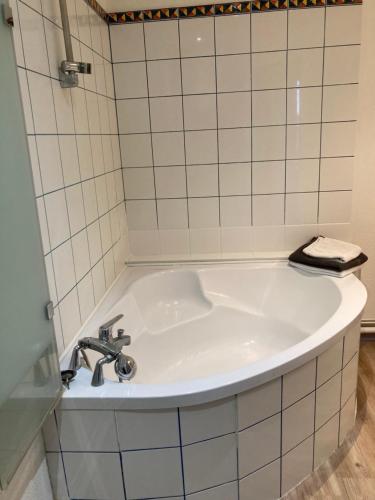 La salle de bains est pourvue d'une baignoire et de carrelage blanc. dans l'établissement Studio fonctionnel, étage 2, proche Techn'hom, IUT et UTBM, à Belfort