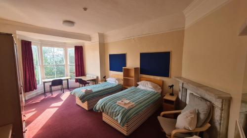 1 dormitorio con 2 camas, escritorio y ventana en St Chad's College en Durham