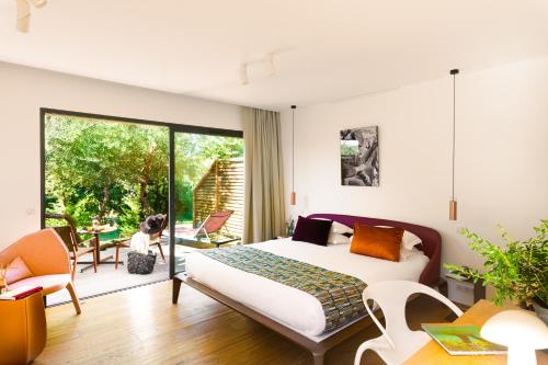 a bedroom with a bed and a sliding glass door at Hôtel & Spa Version Maquis Citadelle in Bonifacio