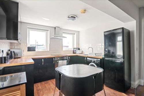 a kitchen with black cabinets and a black refrigerator at Glovers Lodge - Charming 3 Bed Retreat near City Centre in Derby