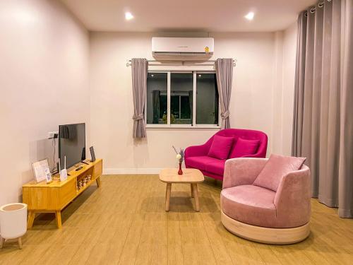 a living room with a pink chair and a tv at Himehome at Suanbanpaeng 