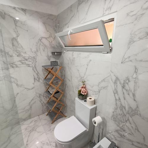 a white marble bathroom with a toilet and a window at AQUAVIEW - VENDA NOVA in Venda Nova