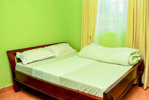 een bed in een kamer met een groene muur bij Nsos apartment in Busia