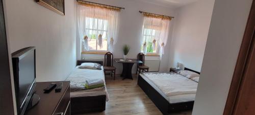 a room with two beds and a table and two windows at Gold Stok in Złoty Stok