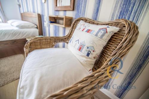a wicker chair with a pillow in a bedroom at Ebb n Flow - 2 Bed - Nature Reserve & Beach Views in Winchelsea