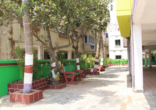 a row of trees and benches in front of a building at HOTEL PURI GREENS in Puri