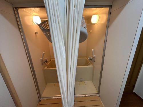 a shower with a curtain in a bathroom at Backpackers' asakusa share house "ASAKUSAGASM" in Tokyo