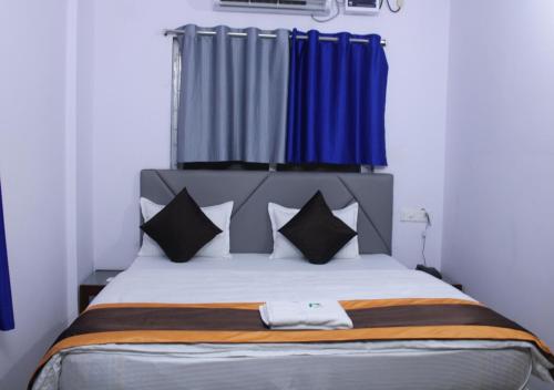 a bedroom with a large bed with blue curtains at HOTEL PURI GREENS in Puri
