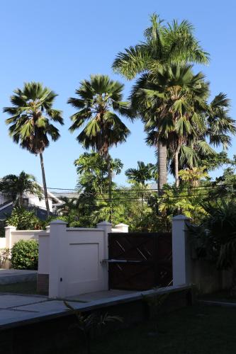 a white gate with palm trees in the background at Hotel La Roussette in Anse aux Pins