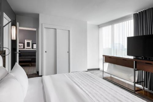 a white bedroom with a bed and a television at Le Meridien Atlanta Perimeter in Atlanta