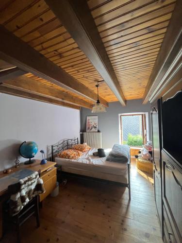 une chambre avec un grand lit et un plafond en bois dans l'établissement Maison auvergnate, à Dauzat-sur-Vodable