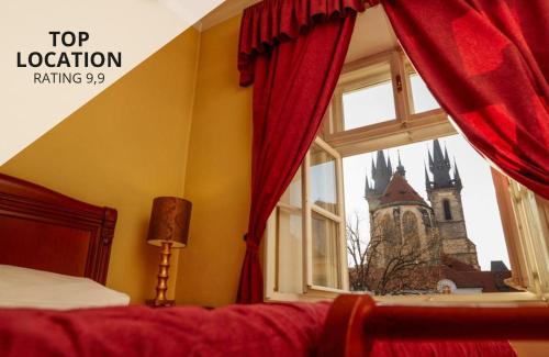 ein Schlafzimmer mit einem roten Vorhang und einem Fenster mit einem Turm in der Unterkunft Josephine Old Town Square Hotel - Czech Leading Hotels in Prag