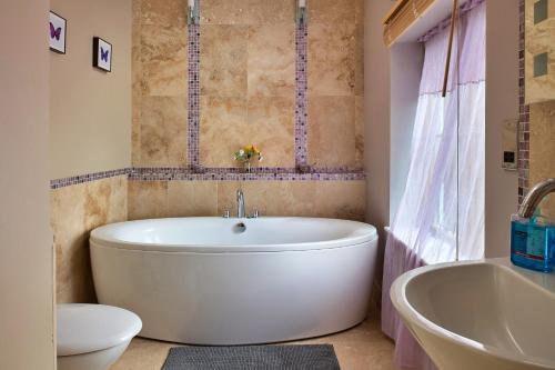 a bathroom with a white tub and a toilet and a sink at Finest Retreats - Buzzards View in Eglwys-Fâch