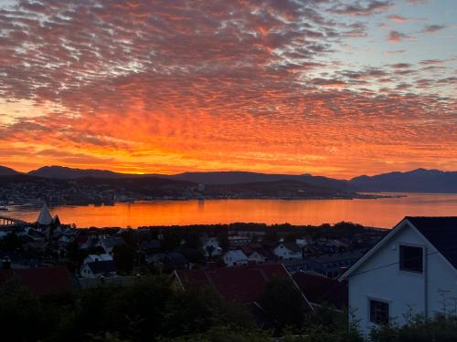 a sunset over a city and a body of water at Apartment Tromsdalen. Tromsø in Tromsø