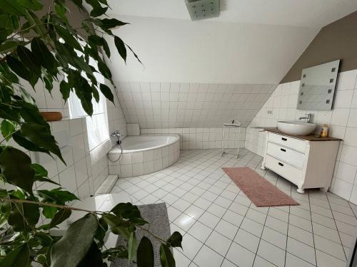 Baño de azulejos blancos con bañera y lavamanos en Erlebnisbauernhof Schwanewede en Schwanewede