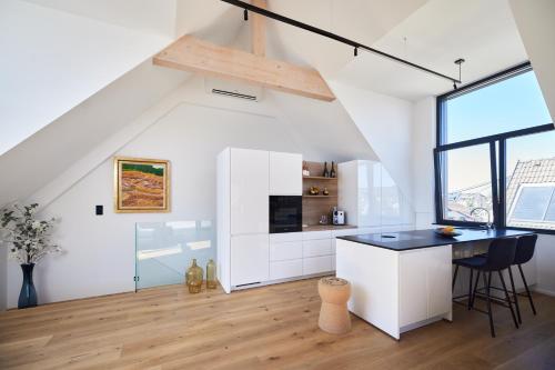 a white kitchen with a counter and a table at Designapartment Salzburg in Salzburg