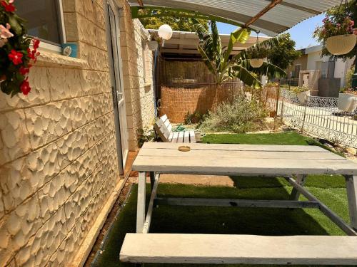 a wooden picnic table in a backyard with a fence at בית בקיבוץ in Hagoshrim