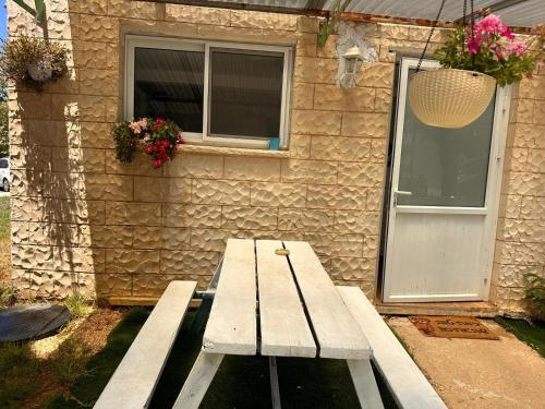 una mesa de picnic de madera sentada frente a un edificio en בית בקיבוץ, en Hagoshrim
