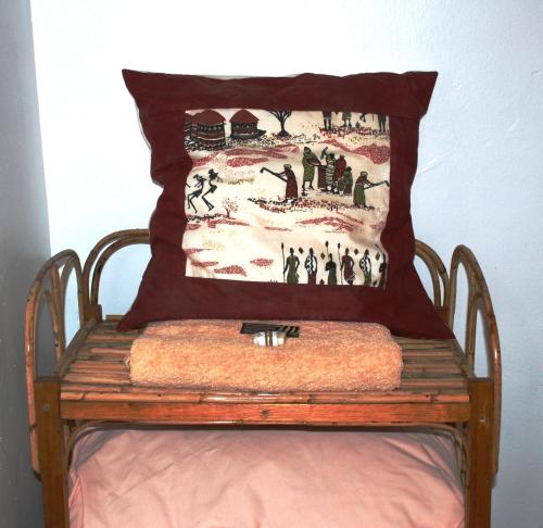a pillow sitting on top of a wooden chair at Alison & Dave's Guesthouse in Entebbe