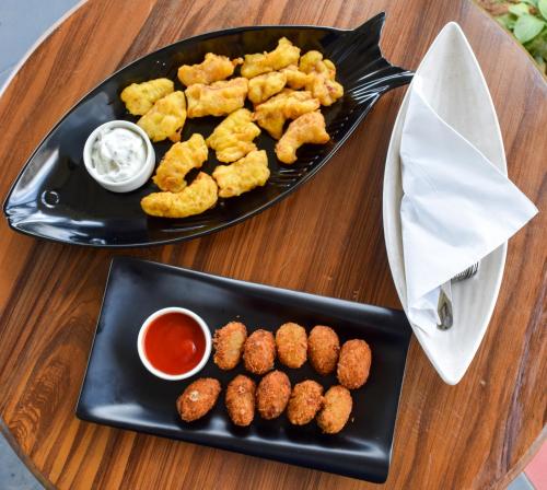 a plate of food with tater tots and dipping sauce at Ibex Resorts, Coonoor Leewood in Coonoor