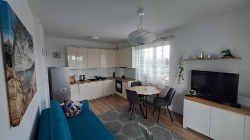 a living room with a blue couch and a kitchen at Nowiutki apartament z bezpłatnym parkingiem in Rumia
