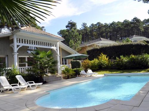 une piscine avec des chaises et une maison dans l'établissement Villa in Lacanau-Océan with Private Pool, à Lacanau