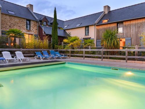 une piscine avec des chaises bleues et une maison dans l'établissement Cancale Port Family Stay, à Cancale