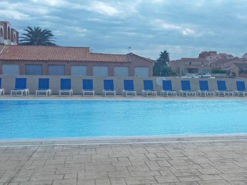 une piscine avec des chaises bleues et un bâtiment dans l'établissement Apartment in Catalana near Mediterranean Beaches, au Barcarès