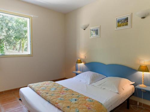 1 dormitorio con 1 cama con cabecero azul y ventana en Air-conditioned maisonette near the center of Gaujac in the Gard, en Gaujac
