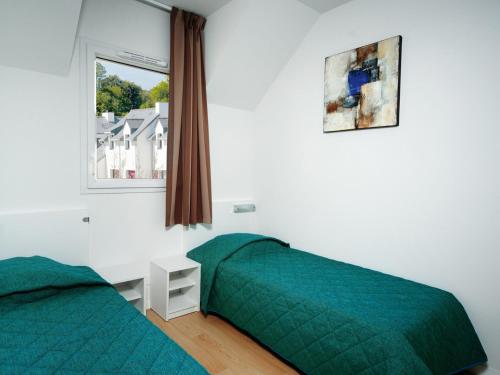 a bedroom with two green beds and a window at Comfortable holiday home close to a golf course in Brittany in Quéven
