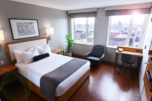 ein Hotelzimmer mit einem Bett, einem Schreibtisch und Fenstern in der Unterkunft Edge Hotel Washington Heights in New York