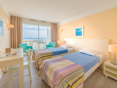 une chambre d'hôtel avec trois lits, une table et des chaises dans l'établissement Apartment in France near Scenic Coastline, à Château-dʼOlonne