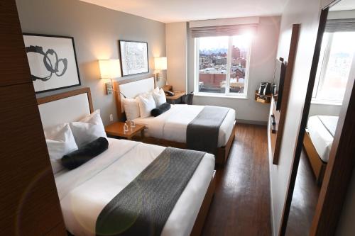 a hotel room with two beds and a window at Edge Hotel Washington Heights in New York