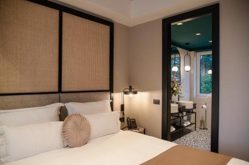 a bedroom with a white bed and a mirror at Palazzo Rainis Hotel & Spa - Small Luxury Hotel - Adults Only in Novigrad Istria