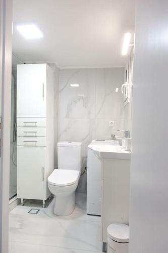 a white bathroom with a toilet and a sink at Downtown supreme apartment kavala in Kavála