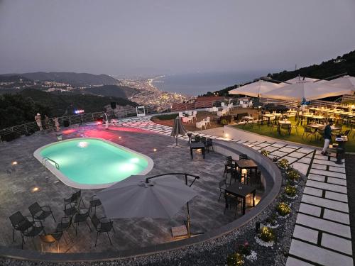 una piscina con tavoli, sedie e ombrellone di Tenuta Croce Appartamento Karol-Piscina-Vista Mare a Salerno