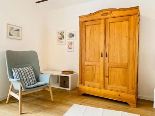 Cette chambre dispose d'une chaise et d'une armoire en bois. dans l'établissement Restaurierter Altbau mit privatem Innenhof & Parkplatz, à Großfischlingen