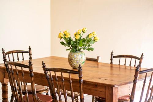 a vase of flowers sitting on top of a wooden table at Charming Historical Cottage in Graaff-Reinet